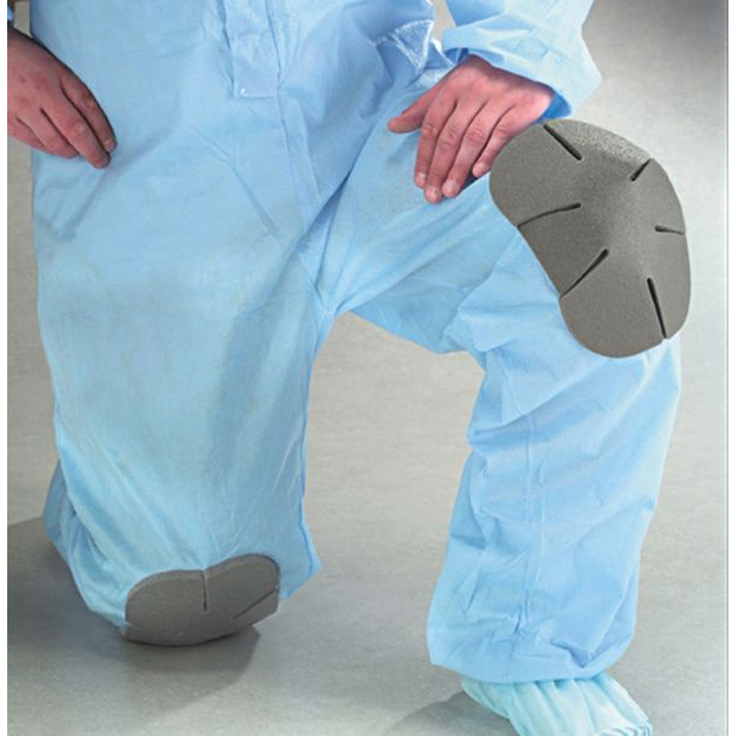 Person wearing blue protective coveralls with gray shoes on a plain background