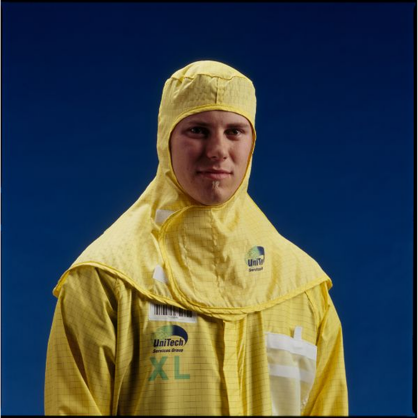 Person wearing a yellow protective hood with visible branding against a blue background