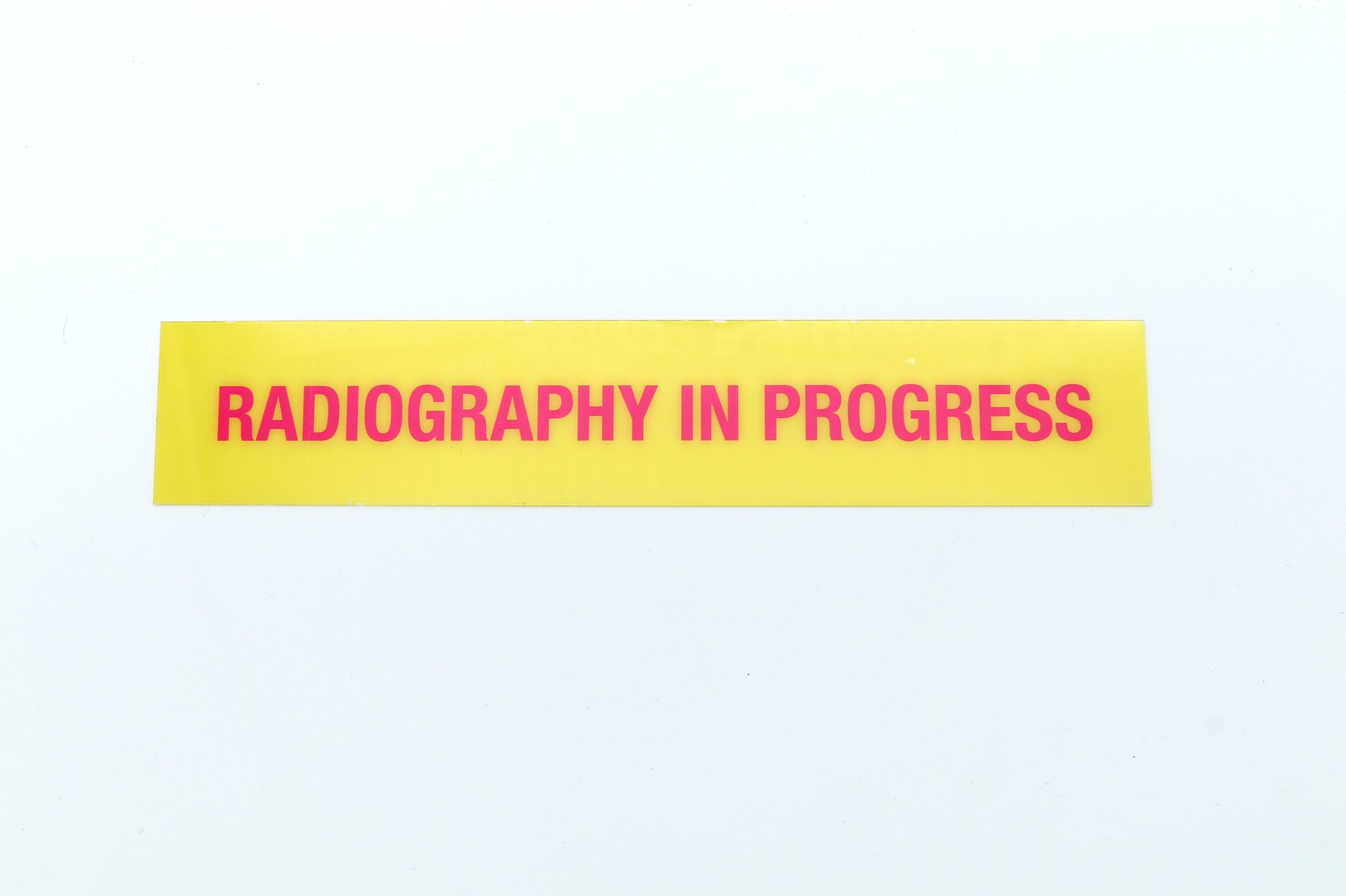 Yellow sign with 'Radiography in Progress' text on a white background