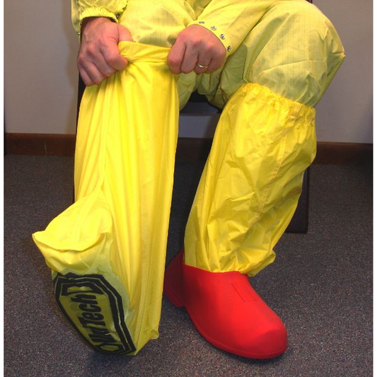 Person wearing a bright yellow protective suit with red boots sitting on a chair.