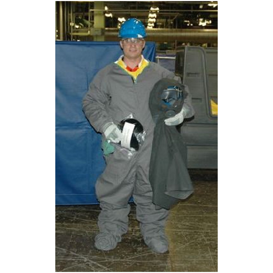 Person in full protective gear holding a helmet and a rolled-up mat in an industrial setting.