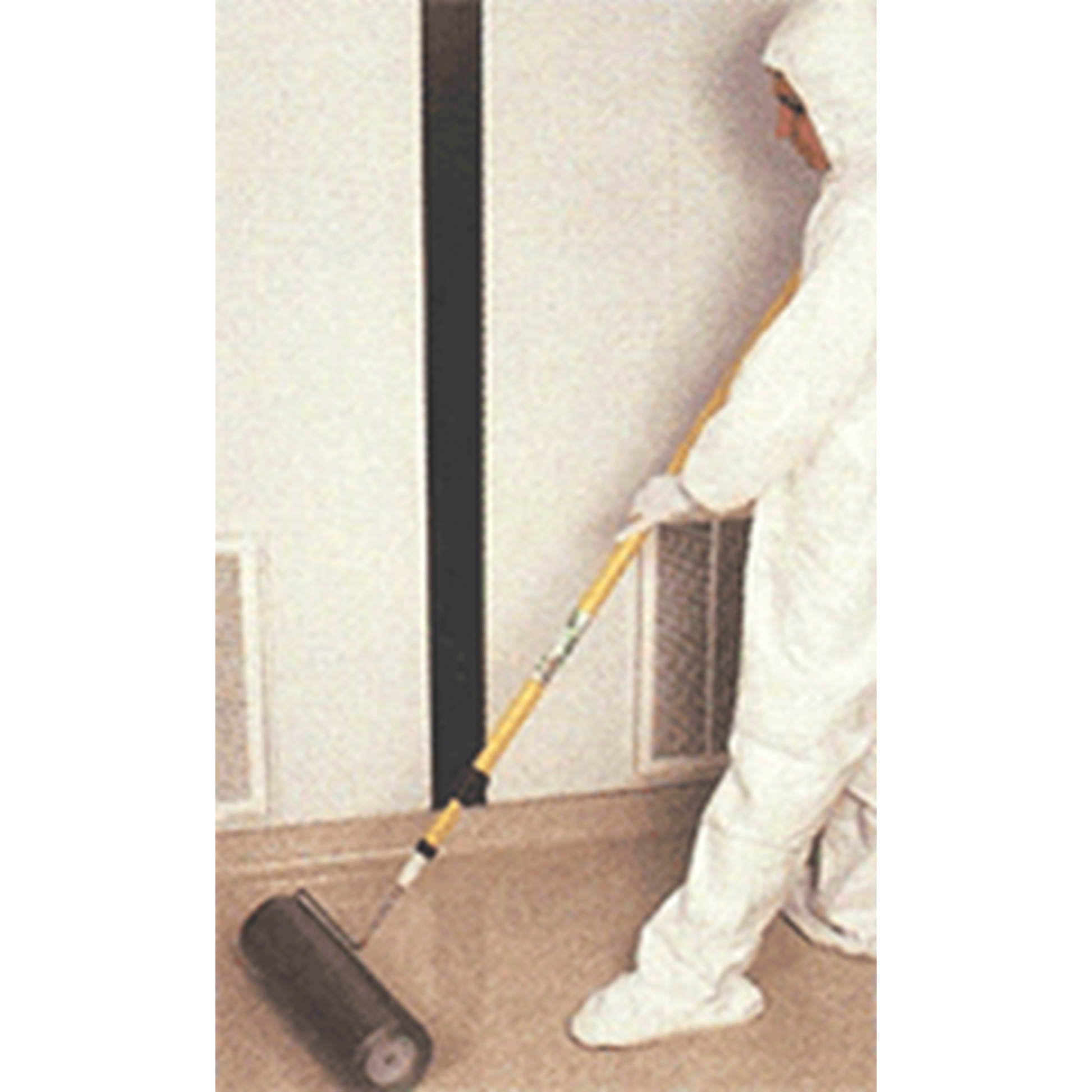 Person in protective gear using a roller to apply a substance on a wall.