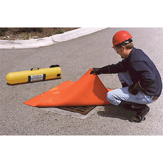 Person setting up an orange safety cone on a road with a yellow cylindrical object nearby.